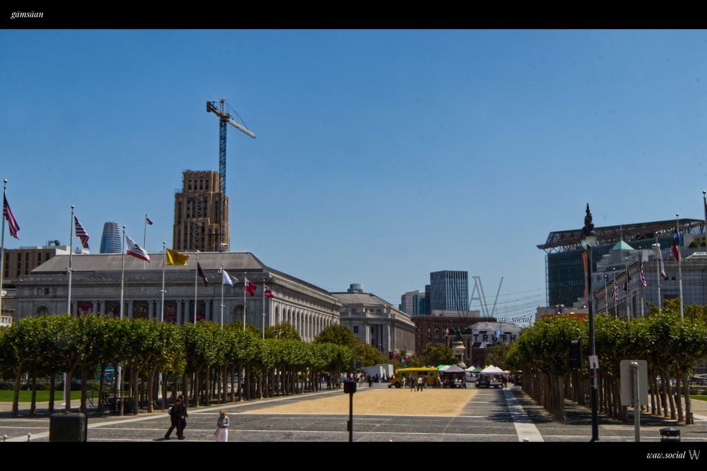 A photo of San Francisco Civic Center and skyline with flags and construction work in frame.