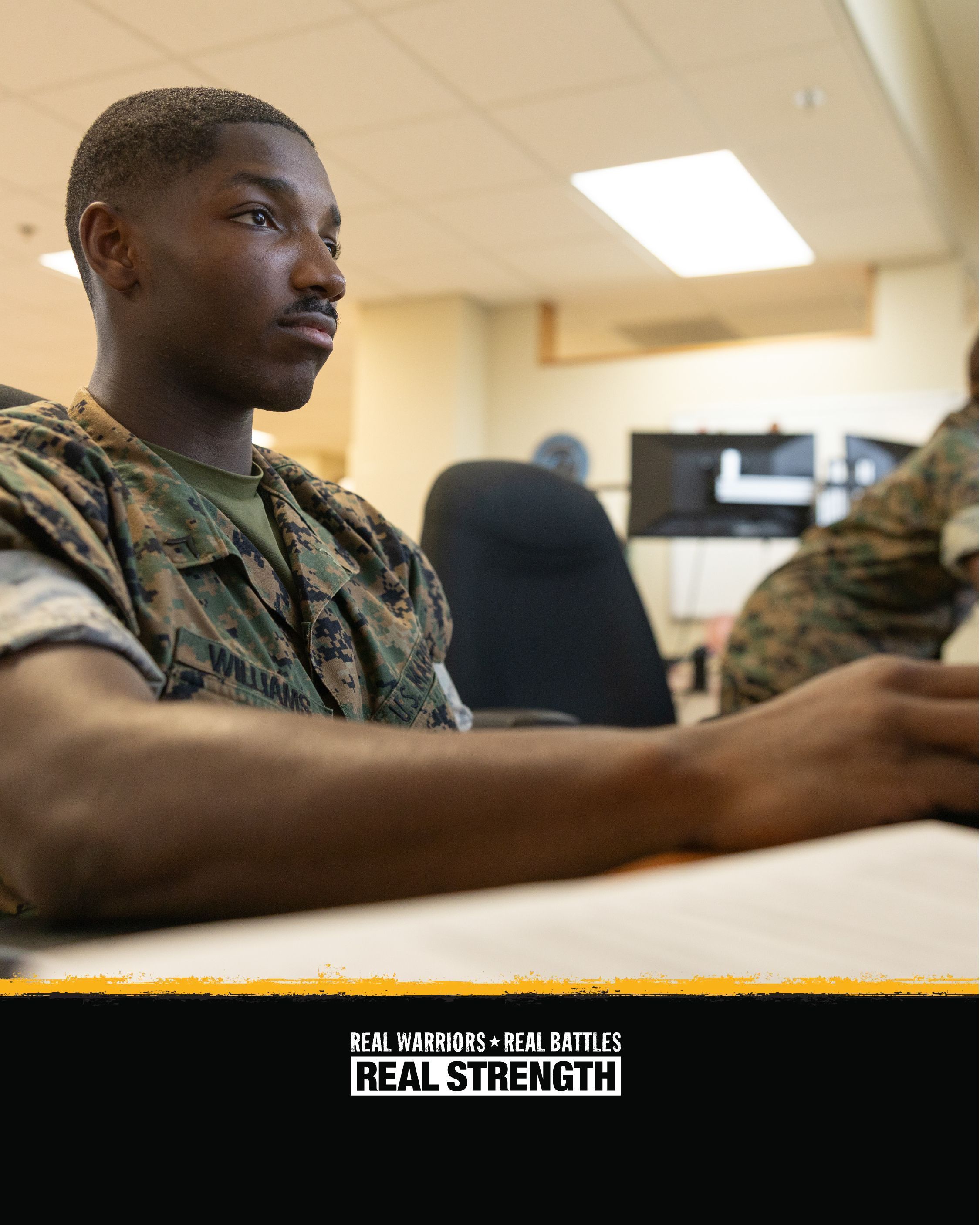 A photo of a service member sitting at a computer with the Real Warriors logo at the bottom.